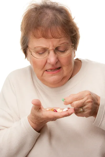 Запутавшаяся пожилая женщина, принимающая таблетки — стоковое фото