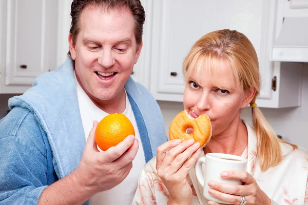 Paar in keuken met fruit en donuts — Stockfoto