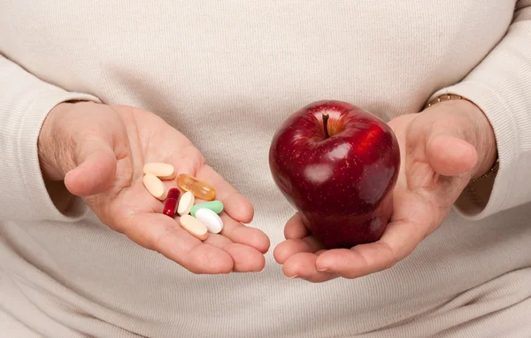 Senior Woman Holding Pills and Apple in her Palms — Stock Photo, Image