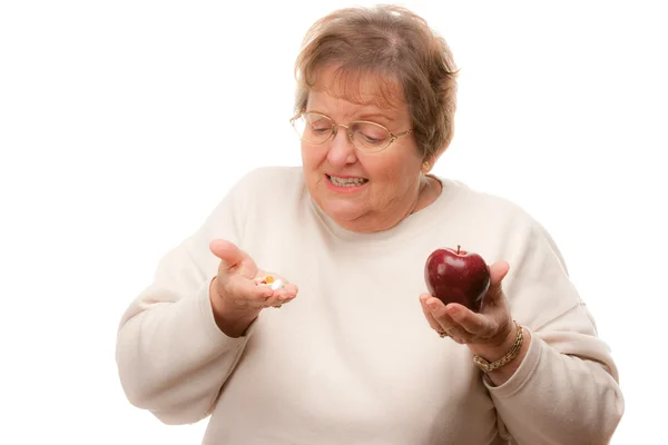 Verward senior vrouw met apple en vitaminen — Stockfoto