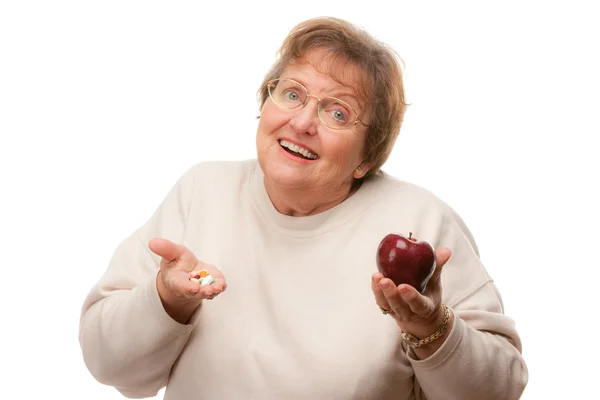 Zmatený dáma drží jablko a prášky — Stock fotografie