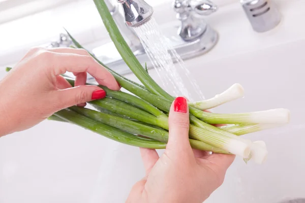 Frau wäscht Zwiebeln in der Spüle — Stockfoto