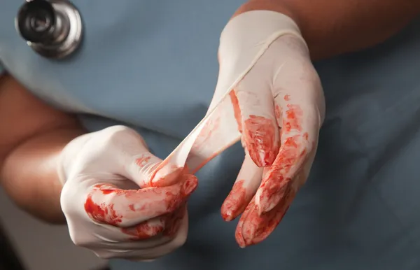 Kirurger blodiga kirurgiska handskar, scrubs, stetoskop — Stockfoto