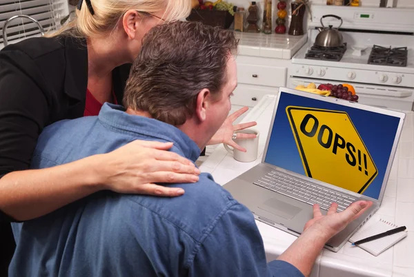 Paar in keuken met laptop met geel Oeps ondertekenen op scherm — Stockfoto