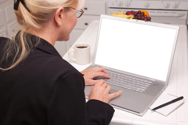 Kobieta siedziała w kuchni za pomocą laptopa z pustego ekranu — Zdjęcie stockowe