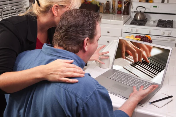 Pareja en la cocina usando ordenador portátil con las manos tocando el piano en la pantalla —  Fotos de Stock