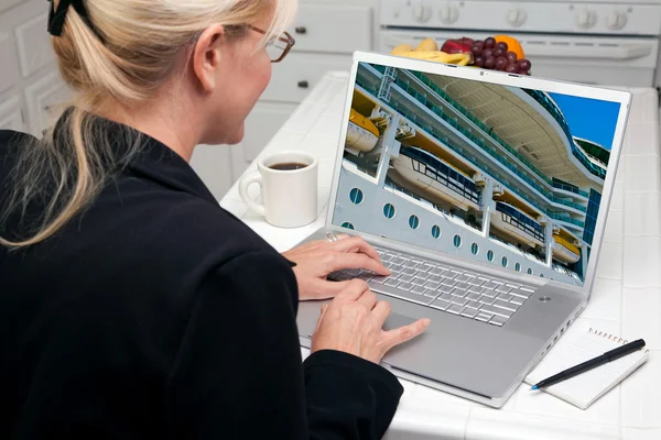 Frau in Küche benutzt Laptop mit Kreuzfahrtschiff auf dem Bildschirm — Stockfoto
