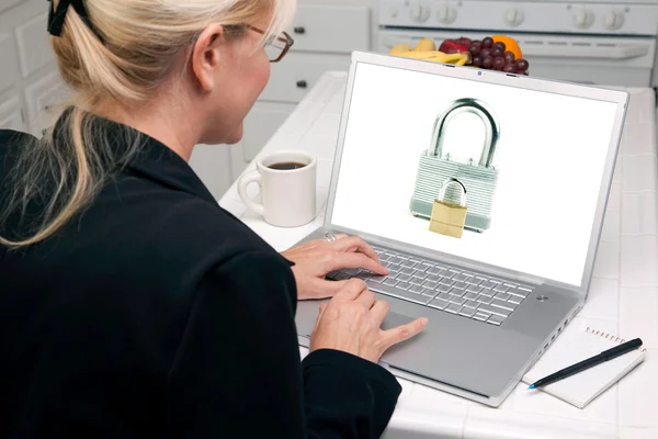 女人在厨房里使用与屏幕上的挂锁的便携式计算机 — 图库照片