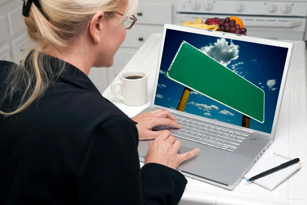 Vrouw in keuken laptop met lege verkeersbord op scherm — Stockfoto
