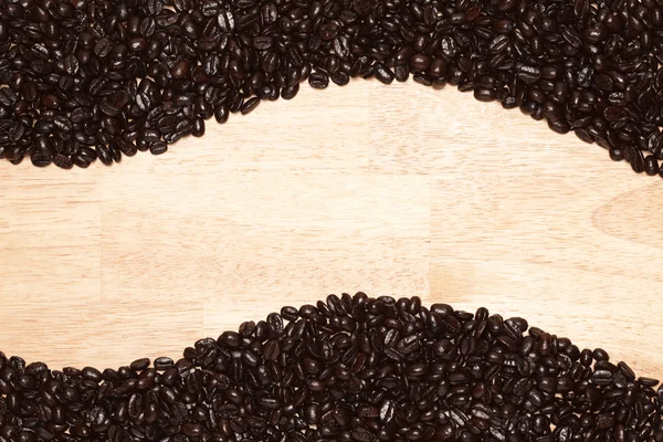 Granos de café tostados oscuros sobre un fondo texturizado de madera —  Fotos de Stock