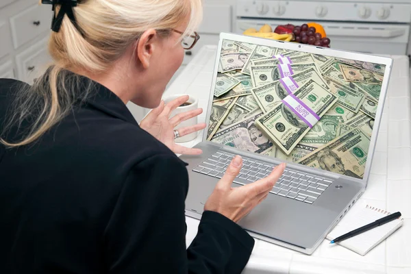 Glada kvinna i köket med laptop att tjäna eller vinna pengar — Stockfoto