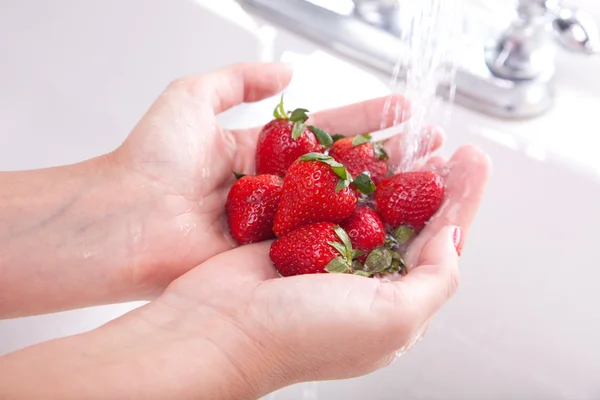 Frau wäscht Erdbeeren in Küche — Stockfoto