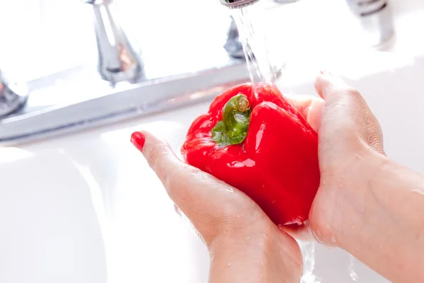 Frau wäscht rote Paprika im Waschbecken — Stockfoto