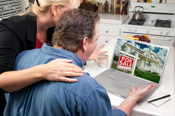 Couple dans la cuisine à l'aide d'un ordinateur portable à la recherche immobilière — Photo