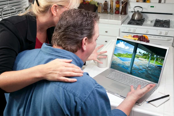 Dvojice v kuchyni pomocí laptopu na výzkumu cestování — Stock fotografie