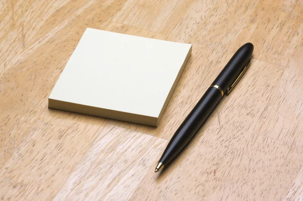 Pen en post-it notes pad tegen hout — Stockfoto