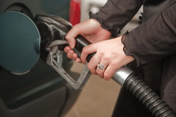Kvinnans händer pumpa bensin vid service station — Stockfoto