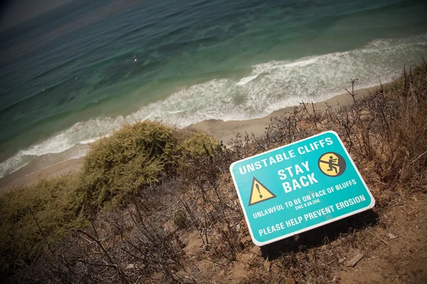 Fique para trás sinal de aviso na borda do penhasco perto do oceano . — Fotografia de Stock