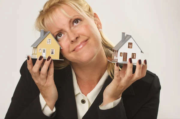 Sorrindo mulher segurando duas casas modelo — Fotografia de Stock