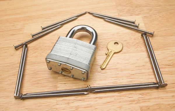 Hus av naglar med lås och nyckel på trä — Stockfoto