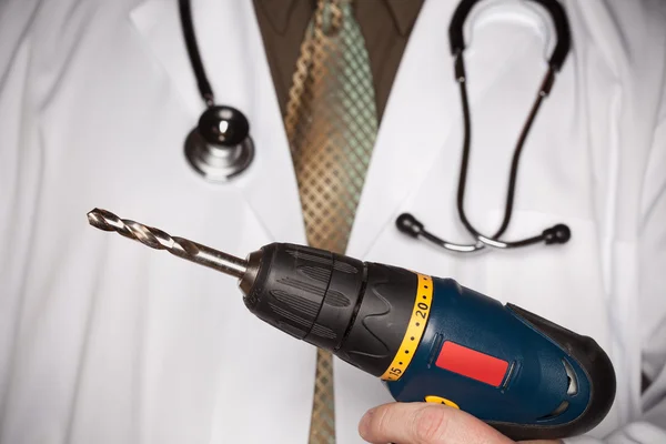 Doutor com estetoscópio segurando uma broca muito grande — Fotografia de Stock