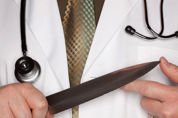 Доктор держит острый кухонный нож — стоковое фото