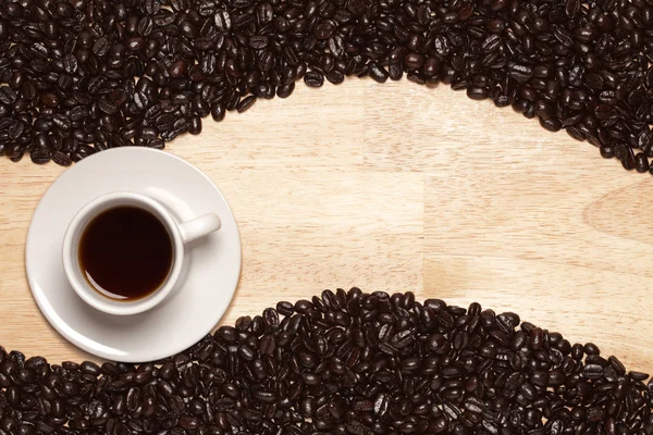 Granos de café tostados oscuros y taza — Foto de Stock