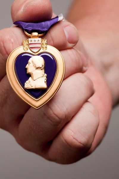 Homem segurando medalha de guerra do coração roxo — Fotografia de Stock