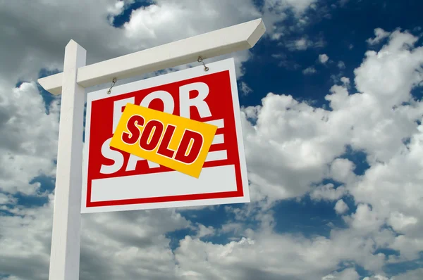 Såld för försäljning fastigheter tecken på moln — Stockfoto