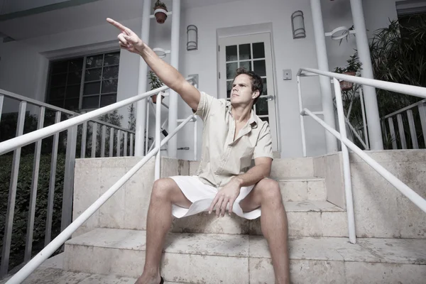 Hombre sentado en las escaleras y señalando su f — Foto de Stock