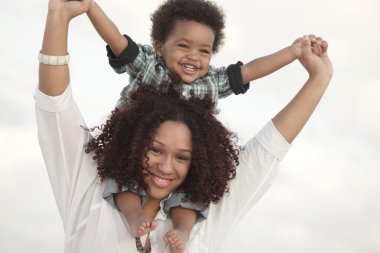 Woman holding her son on her shoulders clipart