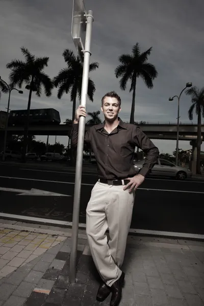Handsome man leaning on a metal pole — Stock Photo, Image