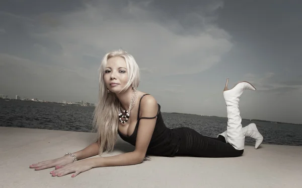 Fashionable young woman posing by the water — Stock Photo, Image