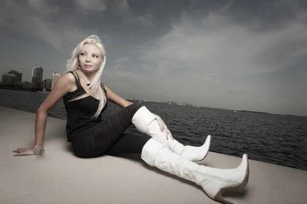 Fashionable young woman sitting by the bay — Stock Photo, Image