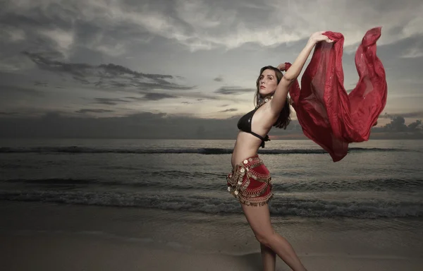 Женщина танцует с красной вуалью у берега — стоковое фото