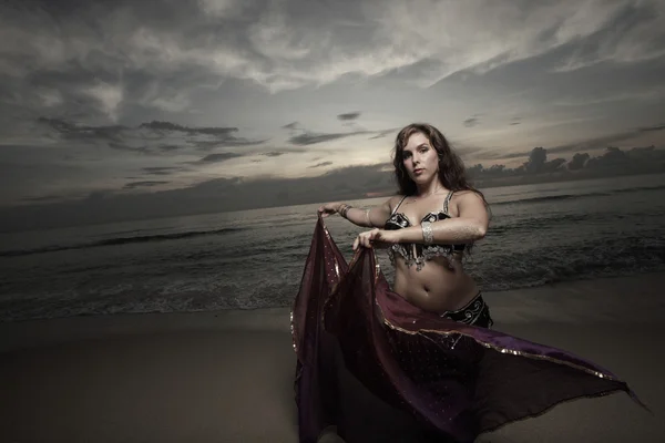 Женщина танцует на пляже с фиолетовой вуалью — стоковое фото