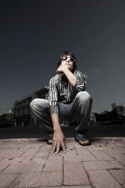 Wide angle image of a man squatting on the street — Stock Photo, Image