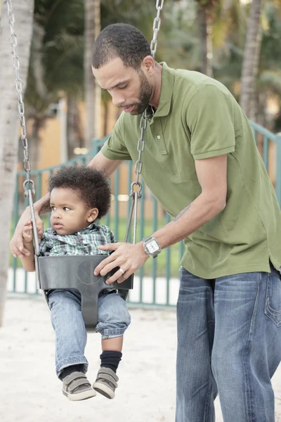 Father placing his son on a swing — Stock Photo, Image