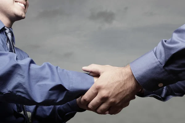 stock image Businessman handshake on a cloudy sky