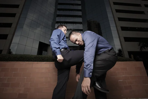 Geschäftsmann kniet einen anderen Geschäftsmann nieder — Stockfoto