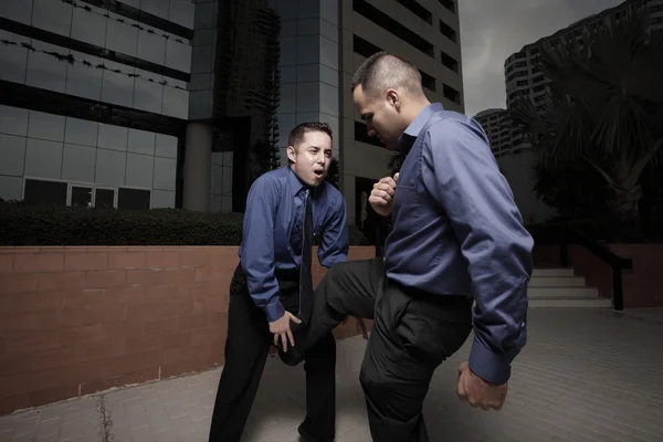 Businessman kicking the other businessman in the groin — Stock Photo, Image