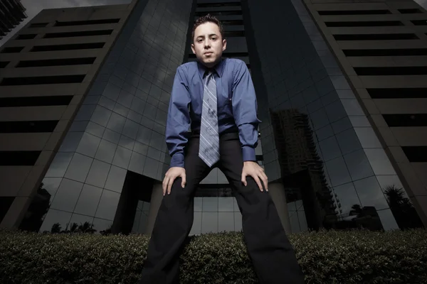 Businessman squatting by a building — Stock Photo, Image