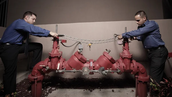 Empresarios tratando de abrir las válvulas de agua —  Fotos de Stock