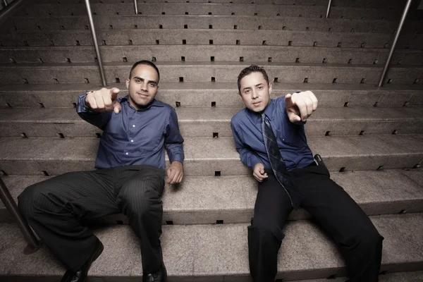 Businessmen sitting on stairs and pointing at the camera — Stock Photo, Image