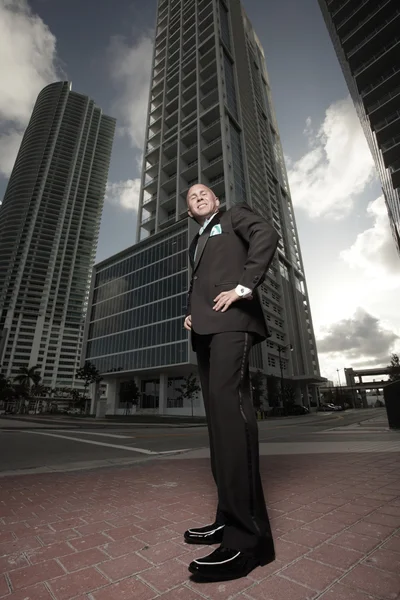Ground angle view of a tall man with luxury high rises in the background — Stock Photo, Image