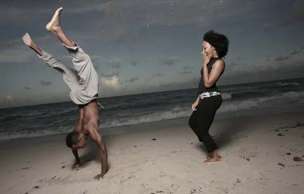 Мужчина выполняет трюки для женщины на пляже — стоковое фото