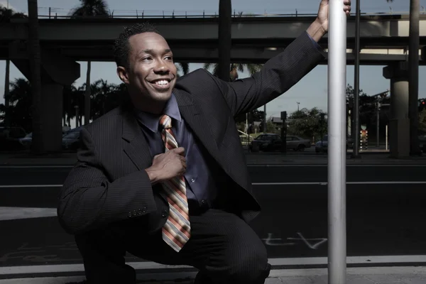 Афроамериканский бизнесмен приседает и улыбается — стоковое фото