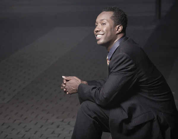 Jonge Afro-Amerikaanse zakenman zitten en glimlachen — Stockfoto