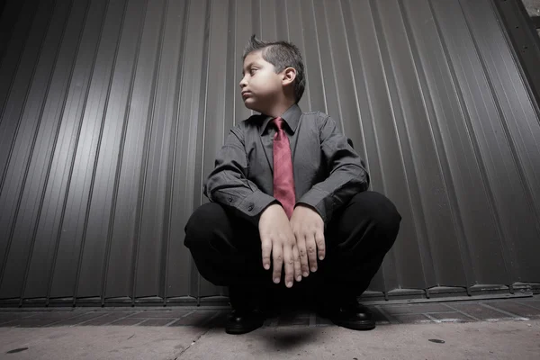 Pojke i business klädsel huk ner — Stockfoto