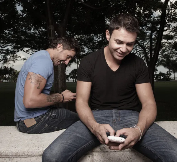 Hombres felices enviando mensajes en sus teléfonos móviles — Foto de Stock